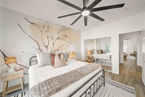 A bedroom with a bed, bedside tables, a ceiling fan, and a large mirror. - Casa Havana  Stunning Views Pool Spa PGA West 4br (La Quinta)