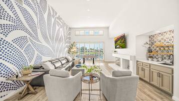 A spacious living area with a large window, a sofa, two armchairs, and a coffee table.