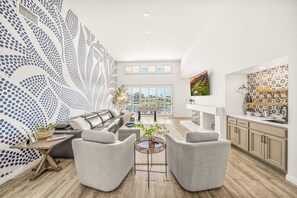 A spacious living area with a large window, a sofa, two armchairs, and a coffee table.