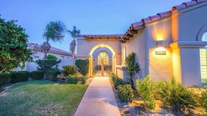 A house with a gated entrance, a well-maintained lawn, and a pathway leading to the door.