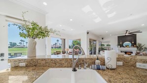 A modern kitchen with a large granite countertop, a stainless steel sink, and a view of the outdoors.