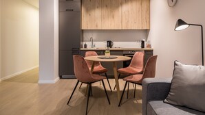 Una cocina moderna con armarios de madera, una mesa redonda con cuatro sillas y un sofá gris con un cojín.