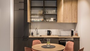 Una cocina moderna con armarios grises, encimera de madera y una zona de comedor con una mesa redonda y dos sillas.