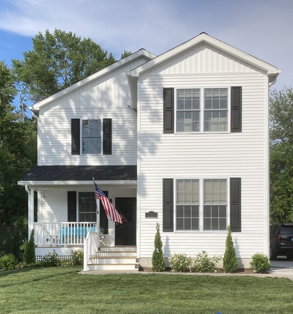 A two-story white house with a front porch, a flag, and a mailbox. - The White House - spacious 5 bedroom, with hot tub - blocks from everything!!!! (New Buffalo)