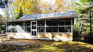 A cabin with large windows, a door, and a porch area.