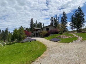 A two-story house with a gravel driveway and a stone pathway leading to the entrance.
