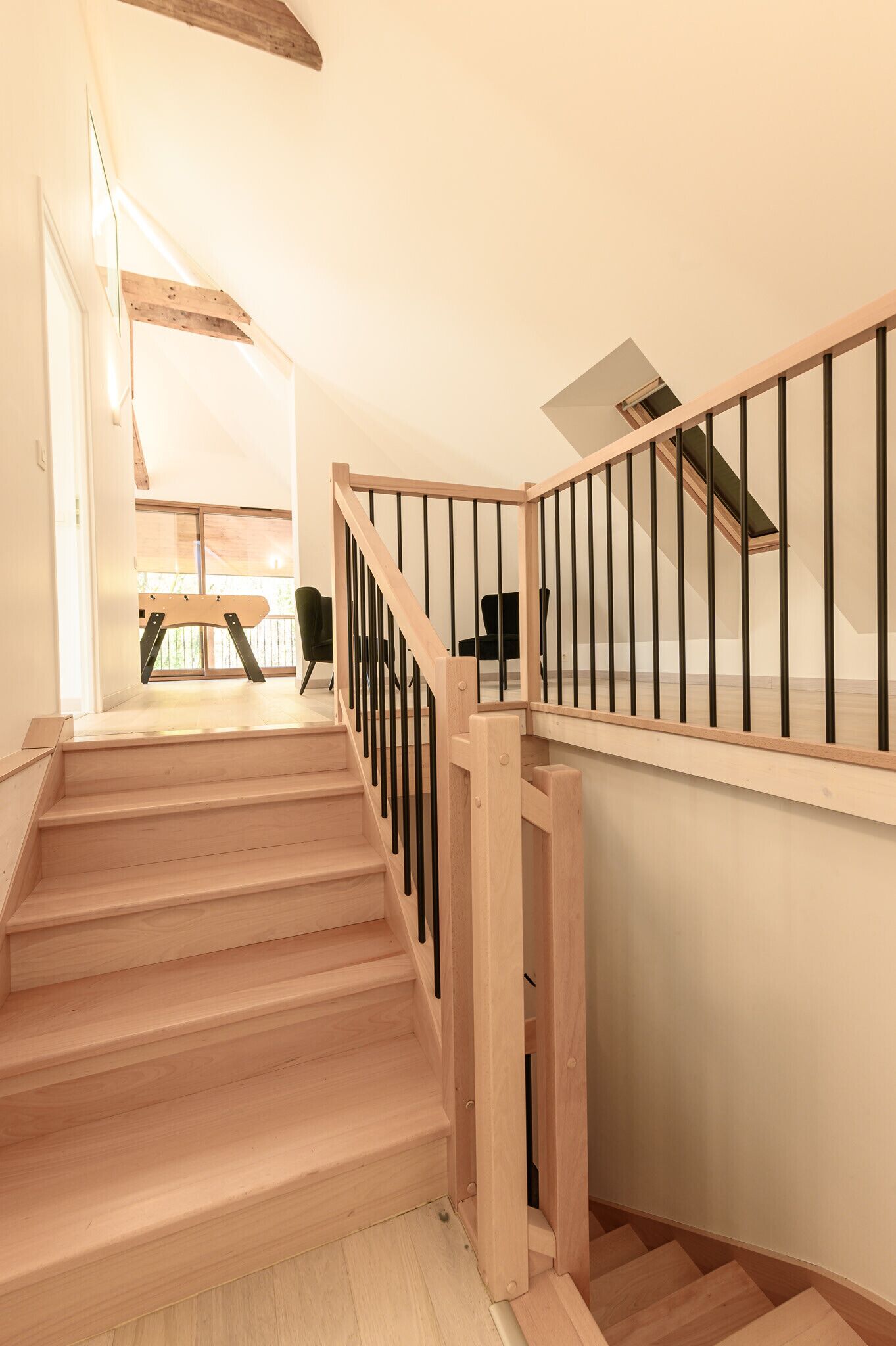 Una escalera de madera con barandillas negras que sube a un piso superior.
