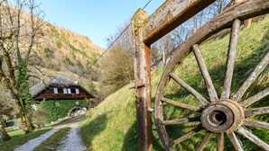 A rustic wooden wheel gate leading to a house with a water wheel, surrounded by a hillside path and greenery. - Le Moulin de Dingy - House with 6 bedrooms & swimmingpool 20 mn from Annecy (Dingy-Saint-Clair)