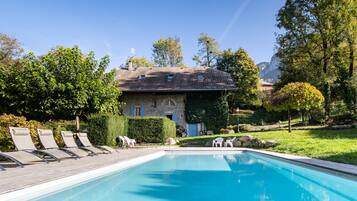 Relax by the serene pool surrounded by lush greenery and trees.