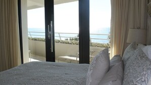 Ein Hotelzimmer mit Bett, einem Balkon mit Meerblick und einem kleinen Tisch mit Stühlen.