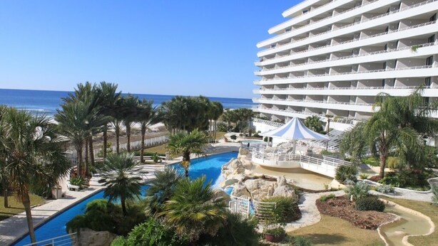 Ein Hotel mit Pool, Palmen und Blick auf den Ozean.