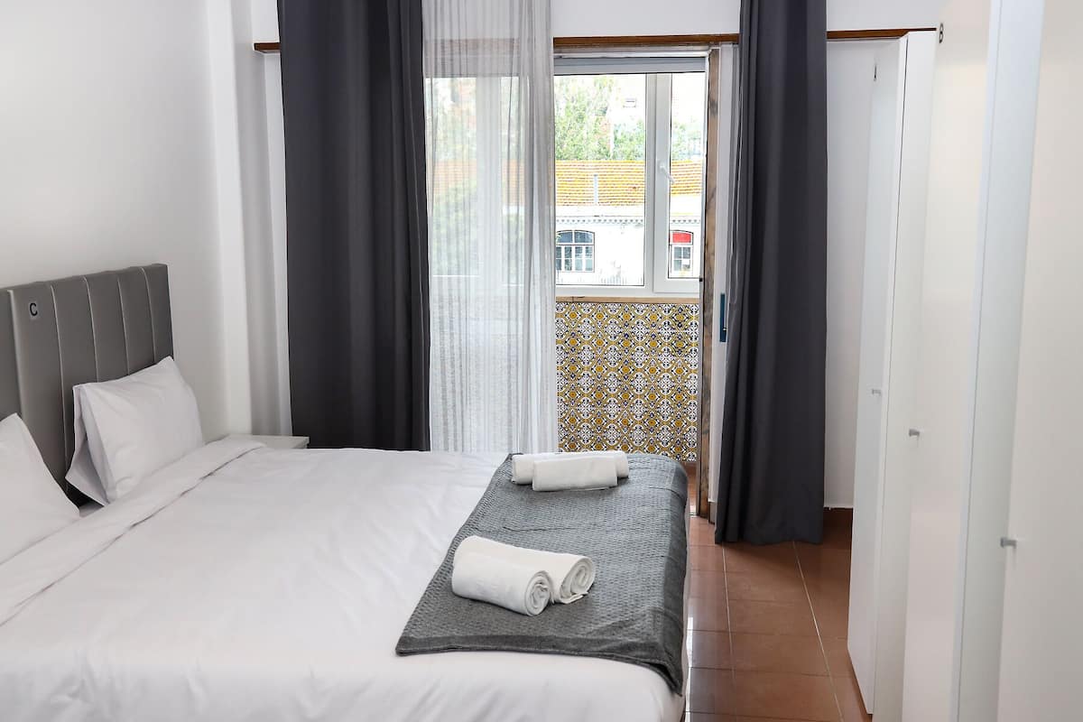 Habitación de hotel con cama, ventana con cortinas y vistas al exterior.