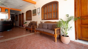 A lobby with a sofa, a potted plant, and wooden doors. - Hotel Bacalar Magico (Bacalar)