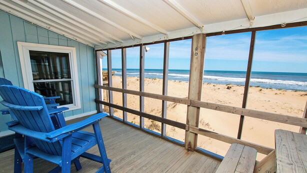 A wooden deck with a view of the beach, a window, and blue chairs. - OCEANFRONT, Ocean Views, Screened porch, KH17, Down by the Sea (Kitty Hawk)