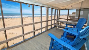 A beachside wooden deck with a view of the ocean, a blue Adirondack chair, and a picnic table. - OCEANFRONT, Ocean Views, Screened porch, KH17, Down by the Sea (Kitty Hawk)