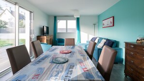 A dining area with a table, chairs, and a television in the background.
