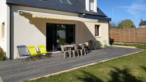 A house with a covered patio, outdoor seating, and a fenced yard.