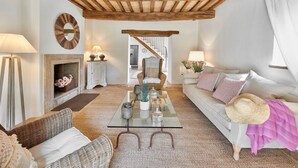A cozy living room with a fireplace, a glass coffee table, wicker furniture, and a staircase leading to another room. - VILLA AMANTA - Nine Bedroom Villa, Sleeps 16 (Perugia)