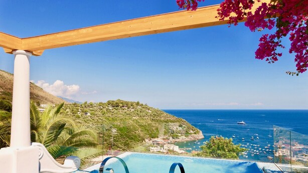 Une piscine à débordement offrant une vue imprenable sur la mer et les bateaux.