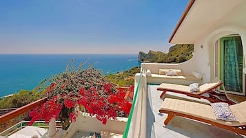 Un balcone con piscina, poltrona a sdraio e vista sul mare.