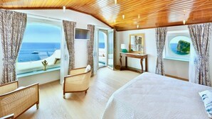 Une pièce spacieuse avec un grand lit, un plafond en bois et une vue sur l’océan.
