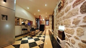 A hotel corridor with a checkered floor, stone walls, a refrigerator, a bar area, and a seating area with chairs. - Apartment with 2 bedrooms with hot tub and water bed (Kotor)