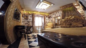 A bedroom with a large bed, a stone wall, a chandelier, and a checkered floor. - Apartment with 2 bedrooms with hot tub and water bed (Kotor)