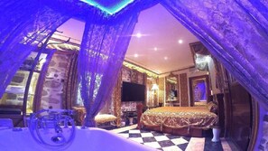 Classic design bedroom with a large bed, flat-screen TV, and elegant chandelier.