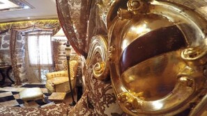 Experience the epitome of luxury with a plush armchair, richly patterned carpet, and ornate mirror.