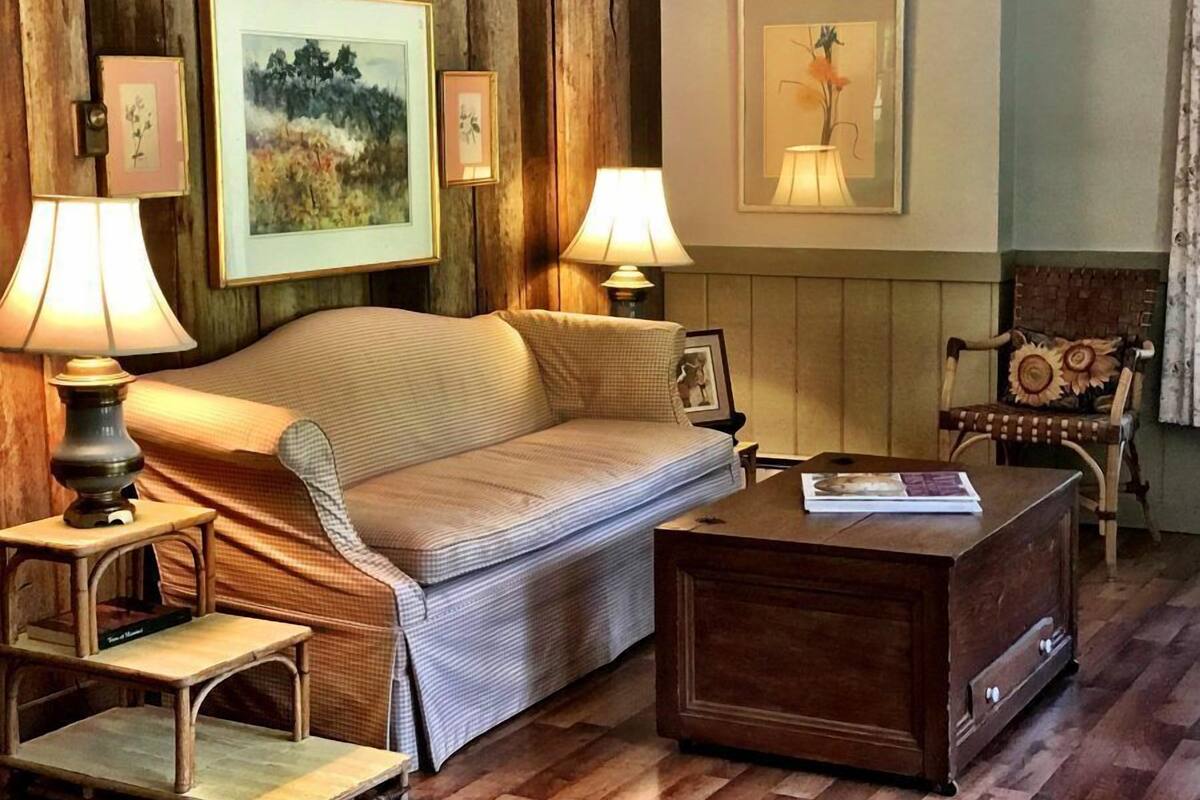 A cozy room with a sofa, two lamps, a small table, and a chair.