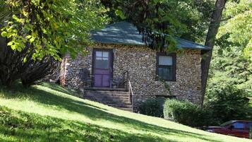 A stone house with a green roof, a purple door, and a small porch with steps.