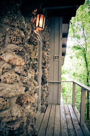 Un muro de piedra con una terraza de madera y un farol.