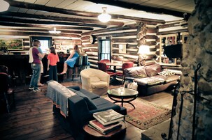 Interior rústico de uma cabana de toras, com área de bar, móveis de madeira e um ambiente acolhedor.