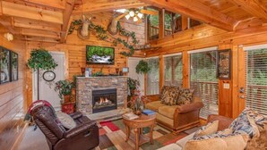 A cozy cabin interior with a fireplace, wooden walls, and a comfortable seating area. - Smokey Max Cabin sleeps 8, hot tub, jacuzzi , pool table (Pigeon Forge)