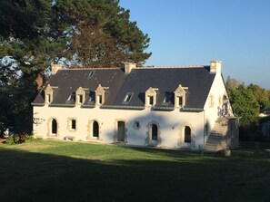 A large, white building with multiple windows and a steeply pitched roof.