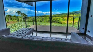 Una habitación moderna con un gran ventanal corredera que da a un balcón con vistas panorámicas de un paisaje exuberante.
