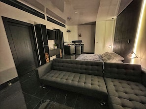 A modern hotel room with a sofa, a bed, a small kitchenette, and a TV. - Inspire Costa Rica (Alajuela)
