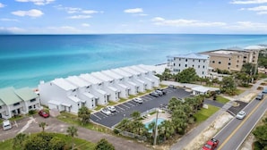 A coastal hotel with a parking lot, a swimming pool, and a view of the ocean. - Blue Tide (Panama City Beach)