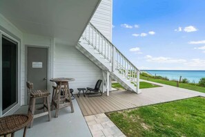 A wooden deck with outdoor furniture, a staircase, and a view of the ocean. - Gulf-Front Condo w/Pool & Beach Chair Access (Panama City Beach)