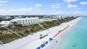 A coastal hotel with multiple white buildings, a sandy beach, and a clear blue ocean. - Blue Tide (Panama City Beach)