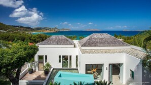 Une villa moderne dotée d’une piscine, d’une façade blanche et offrant une vue sur l’océan.