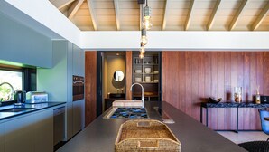 Een moderne keuken met een centraal eiland, ingebouwde apparaten en een houten accentmuur.