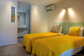 Ein Hotelzimmer mit zwei Betten, einem Badezimmer und einer Klimaanlage.