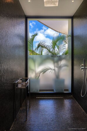 Ein modernes Badezimmer mit großem Fenster, einer Dusche und einem kleinen Tisch.