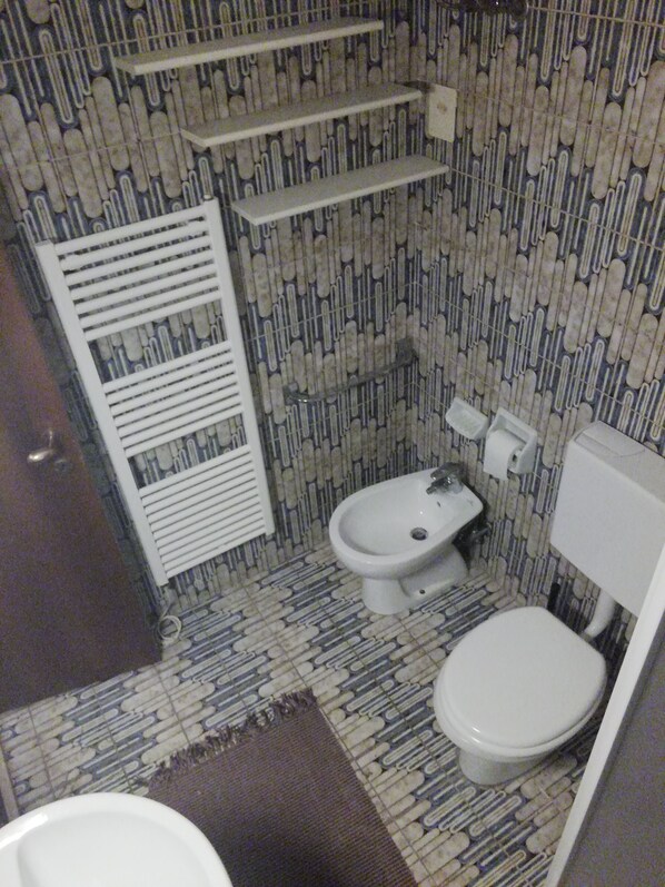 Een badkamer met een vloer met patroon, een toilet, een bidet en een handdoekhouder.
