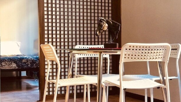 Une pièce comprenant un lit, un bureau, deux chaises, une lampe et un panneau décoratif mural.
