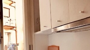 Une cuisine dotée d’un évier en acier inoxydable, d’un bloc à couteaux et d’une fenêtre donnant sur un balcon.