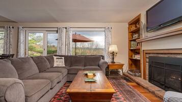 A living room with a sectional sofa, a wooden coffee table, a fireplace, and a large flat-screen TV.