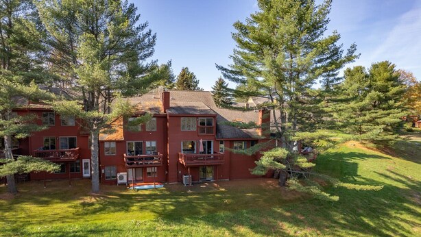 A multi-story red building with balconies, surrounded by trees and grass. - Townhome with Fireplace & Hill Views, Saltbox (Hartford)