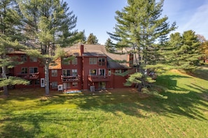 A multi-story red building with balconies, surrounded by trees and grass. - Townhome with Fireplace & Hill Views, Saltbox (Hartford)